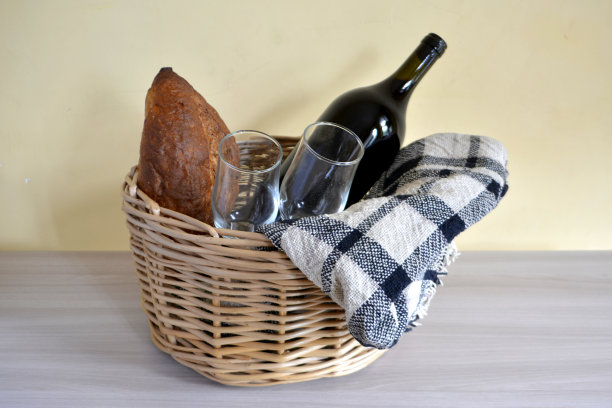 柳条野餐篮子，毯子，一瓶酒，面包和玻璃杯图片下载