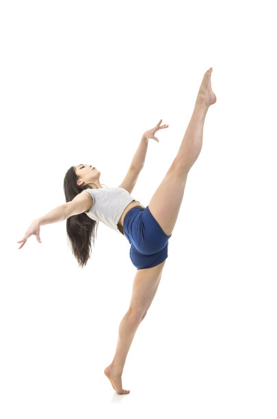 一个穿着短裤和t恤的年轻女孩正在跳现代芭蕾。工作室拍摄的白色背景。图片下载