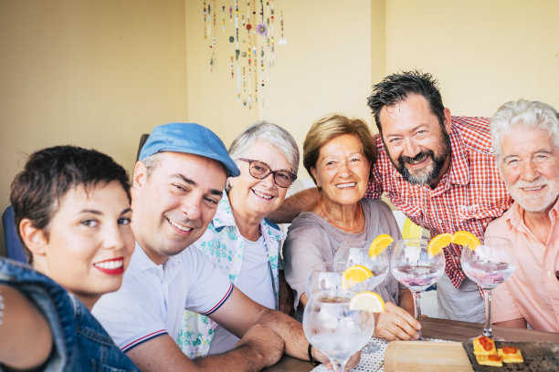 用手机自拍。一群欢天喜地的不同年龄的人们聚在一起用鸡尾酒和食物庆祝。微笑的人们在室外露天阳台快乐。男女休闲活动图片下载