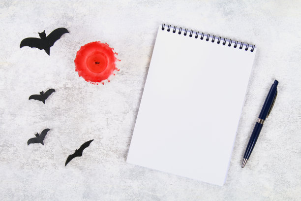 空笔记本，血烛，笔和蝙蝠在一个轻桌上。万圣节的概念。图片下载