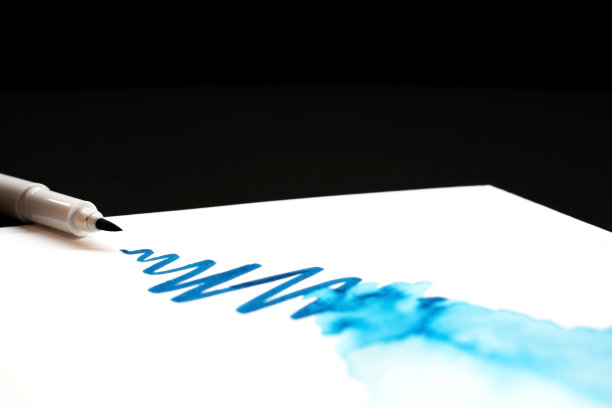 水彩笔笔抹蓝色油漆，在纸上泼墨，特写图片下载