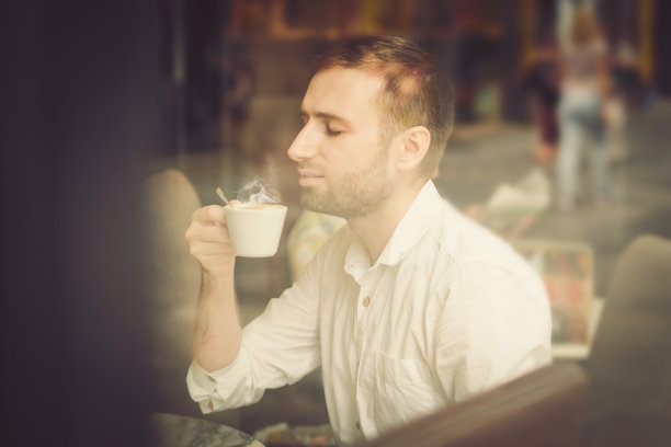 一个年轻人坐在咖啡店里图片下载