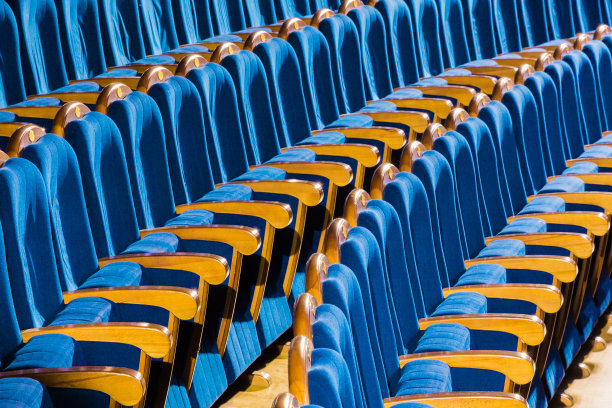 礼堂里有木制扶手的蓝色长毛绒椅子。剧院里空荡荡的礼堂图片下载