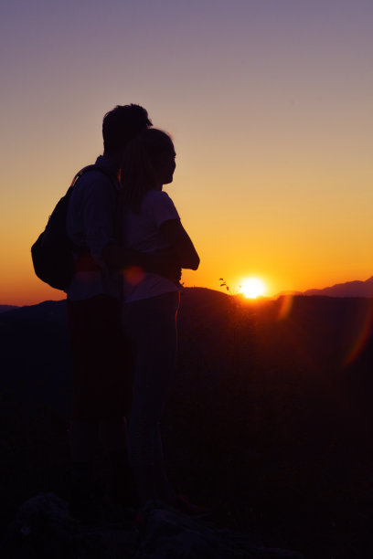 一对年轻夫妇在山上看壮丽的日落图片下载