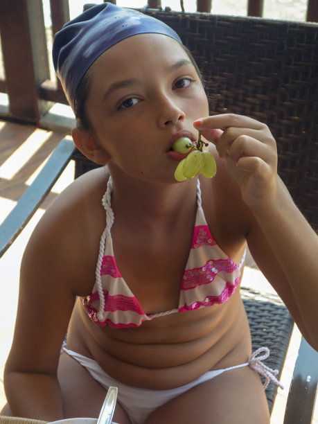 少女在海滩边吃着葡萄图片下载