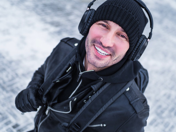 戴着耳机微笑的游客走在街上。冬天的时间。图片下载