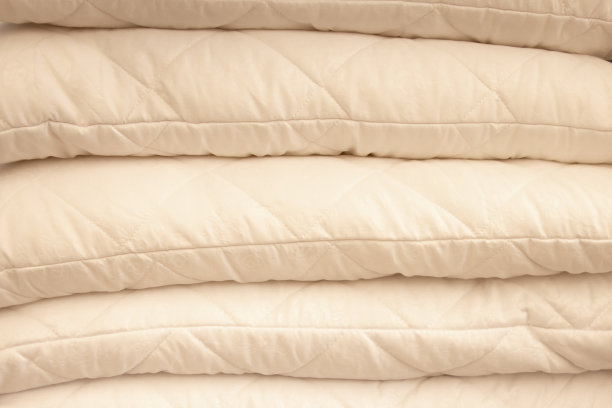 以条纹墙为背景的白色架子上堆着温暖的格子图案和枕头图片下载