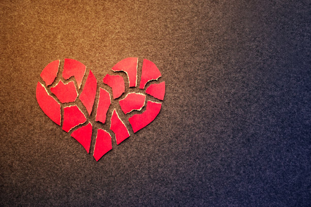 纸上红色的心碎在黑暗的感觉背景。马赛克纸心碎片。破碎的心的象征。破碎的爱的概念。本空间图片下载