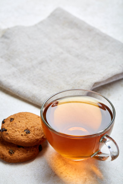 俯视图的近距离图片茶在透明的杯子与巧克力片饼干在棉花餐巾上的白色背景图片下载