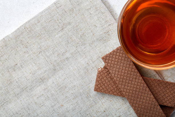 俯视图特写图片的茶在透明的杯与饼干和棉餐巾在白色的背景，选择焦点图片下载