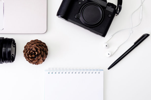 办公桌工作与笔记本电脑键盘，时髦的相机，镜头，笔记本书写与黑色的笔在白色的背景。平躺，俯视图。复古复古的照片风格。图片下载