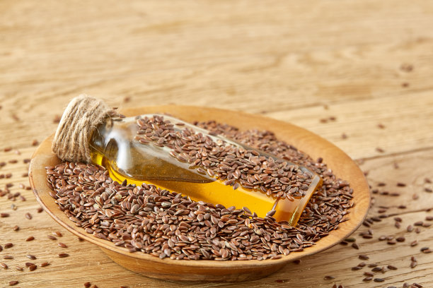 俯视图特写图片亚麻籽和亚麻籽油在一个玻璃瓶上的木制背景，浅景深的领域。图片下载