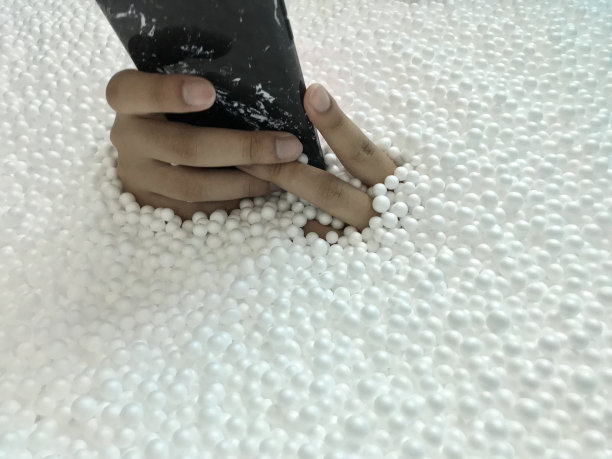 男子手持手机白色泡沫珠子背景图片下载