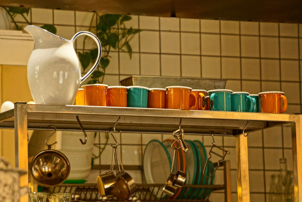 厨房的架子上放着一个白色的大水壶和一排彩色的杯子图片下载