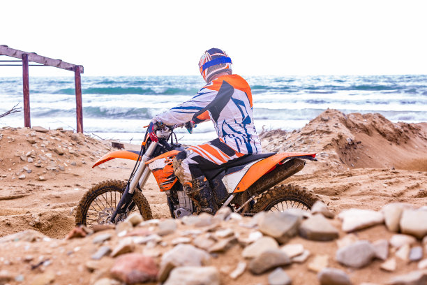 一个穿着防护服的摩托车手坐在大海前面图片下载