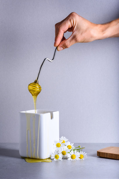 蜂蜜，将健康甜美的花蜜倒入一个白色的罐子里图片下载