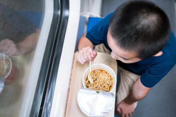 亚洲男孩乘火车旅行，吃着方便面图片下载