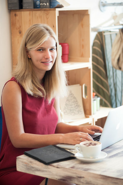 年轻的金发女人在咖啡馆里输入笔记本电脑图片下载