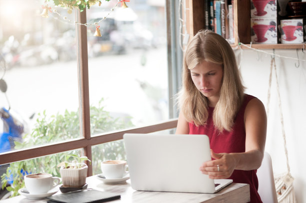 年轻的金发女人在咖啡馆里输入笔记本电脑图片下载