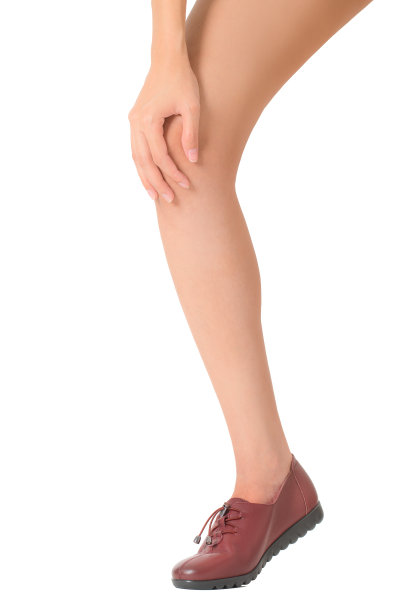 女人抱着她美丽健康的长腿按摩膝盖疼痛的区域，孤立在白色的背景。图片下载