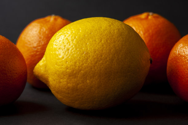 黄色的柠檬和桔子孤立在黑色的背景。图片下载