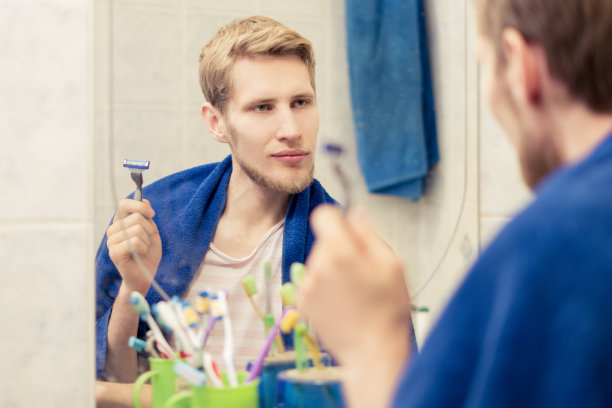 近距离观察年轻的胡子男子使用剃须刀剃须在早上洗澡图片下载