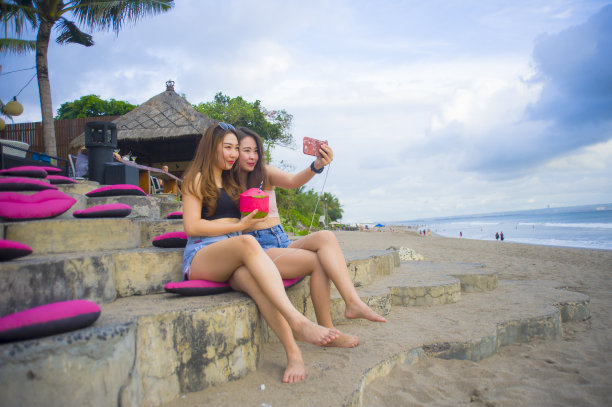 生活方式的肖像，两个年轻的快乐和有吸引力的亚洲中国和韩国女人闲逛，女朋友享受热带度假旅行与手机自拍照片图片下载