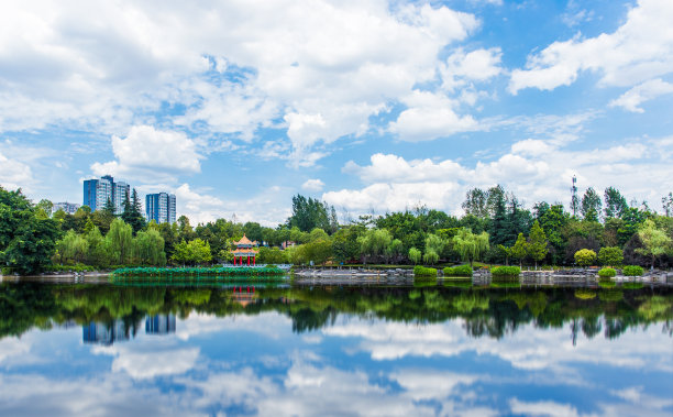 公园里的大学校园里，宁静的湖面和郁郁葱葱的森林，在一个晴朗的夏日，树林映在湖面上图片下载