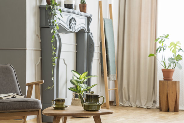 水壶放在木桌上，旁边是灰色的扶手椅，复古的客厅内部有植物。真实的照片图片下载