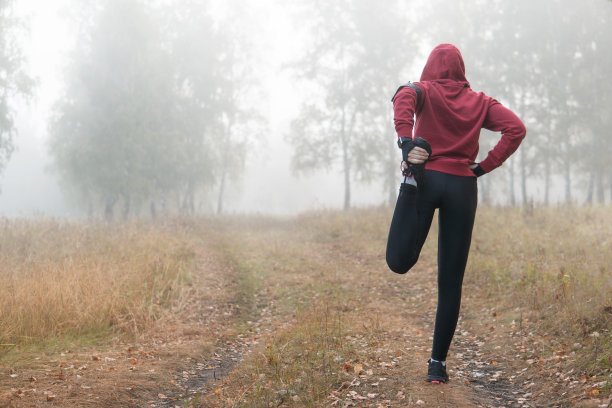 跑步伸展运动——女子跑步者在公园里做运动。图片下载