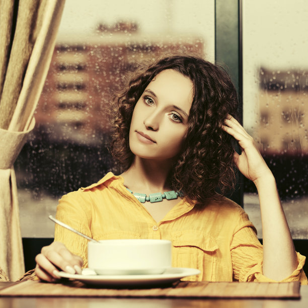 穿着黄色衬衫的快乐年轻女子在餐厅吃汤图片下载