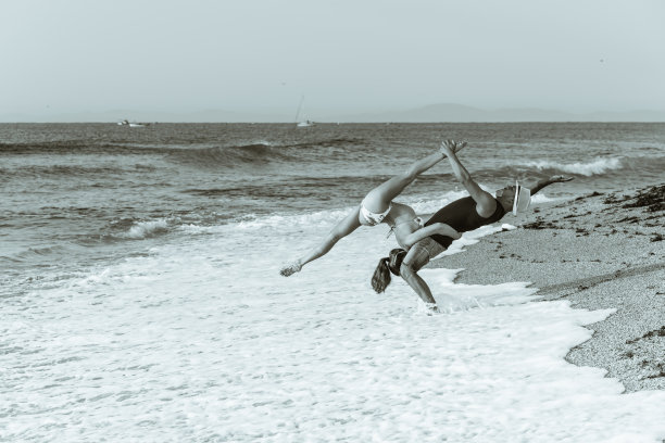 黑白照片，两个灵活的马戏团演员，男和女杂技演员在海边练习体操早上，在一个沙滩上。图片下载