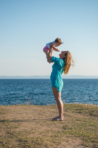 幸福的家庭。年轻美丽的母亲和她的女儿在海滩上玩图片下载