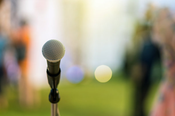 舞台上的麦克风上方是抽象模糊的绿草照片，以散景的灯光为背景，音乐和表现理念图片下载