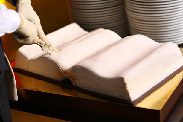 大书形生日蛋糕与厨师的手图片下载