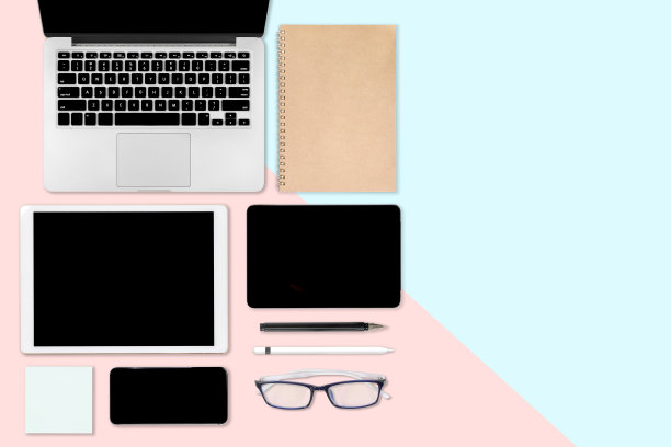 平放办公桌子与笔记本电脑，数字平板电脑，手机和配件的照片。对现代的两种色调(蓝色和粉色)背景。桌面办公室模型概念。图片下载