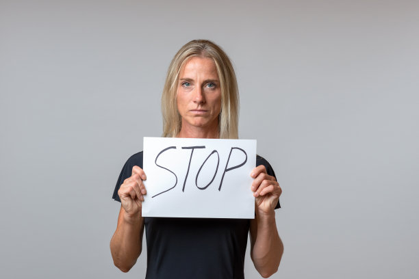 成熟的女人拿着白色的纸上写着“停止”图片下载