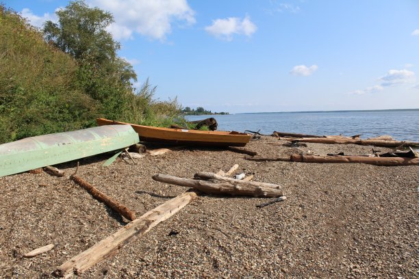 照片渔船躺在美丽的岸边的石头和沙子钓鱼和散步在河，湖。图片下载