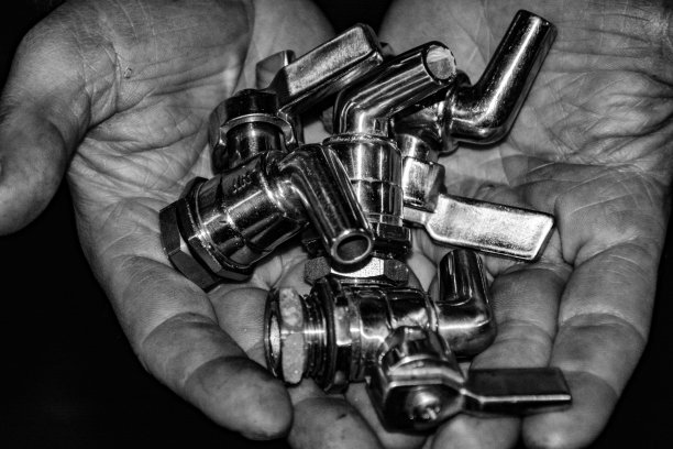 新银水龙头。手里拿着几个装酒桶的水龙头，准备放在酒桶上，开始生产葡萄酒。图片下载