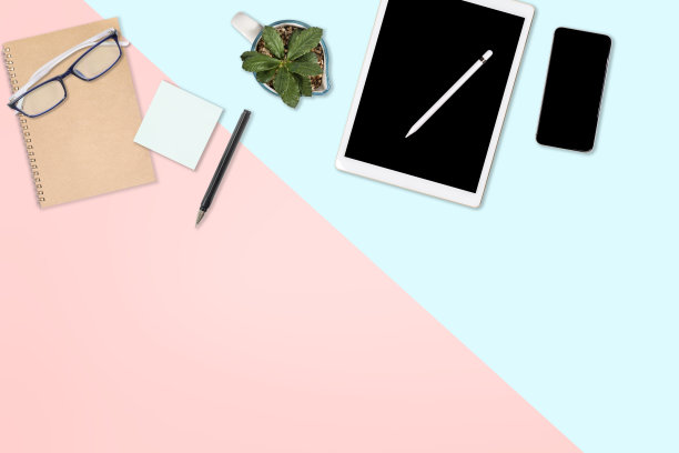 平放办公桌子与笔记本电脑，数字平板电脑，手机和配件的照片。对现代的两种色调(蓝色和粉色)背景。桌面办公室模型概念。图片下载