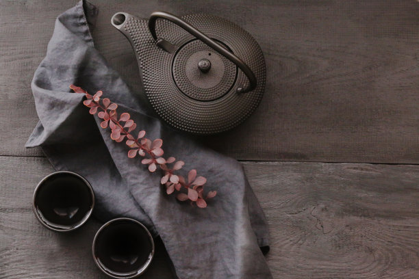 极简风格的秋茶。亚洲风格的黑色茶壶和两杯茶与紫红色细枝上的黑色餐巾在黑色的木制背景。秋天的季节。秋天的时间图片下载