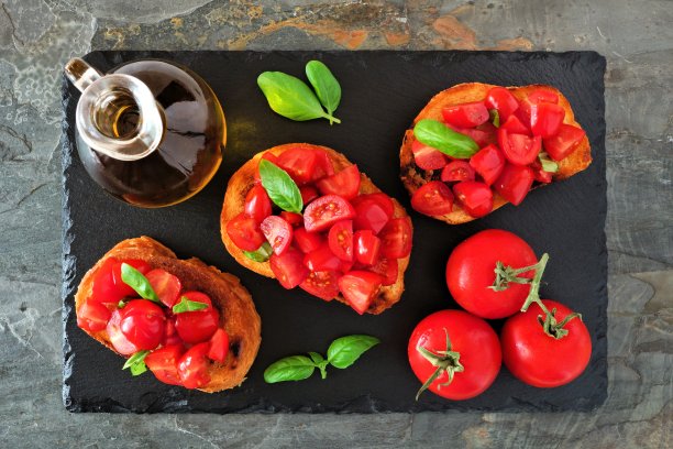 烤面包加番茄和罗勒，上面的场景在一个深色的大浅盘上图片下载