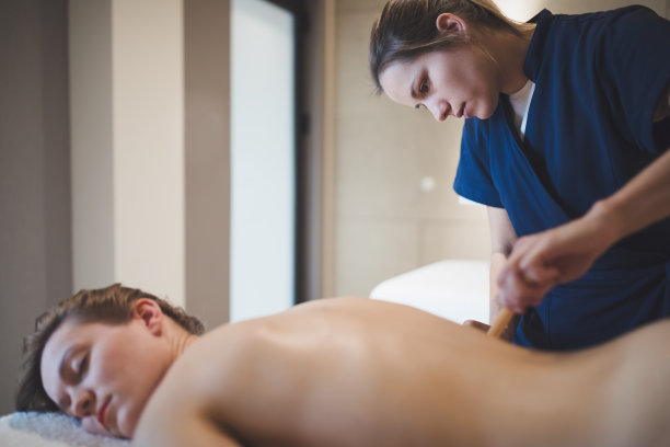 按摩师使用木制工具对病人进行按摩图片下载