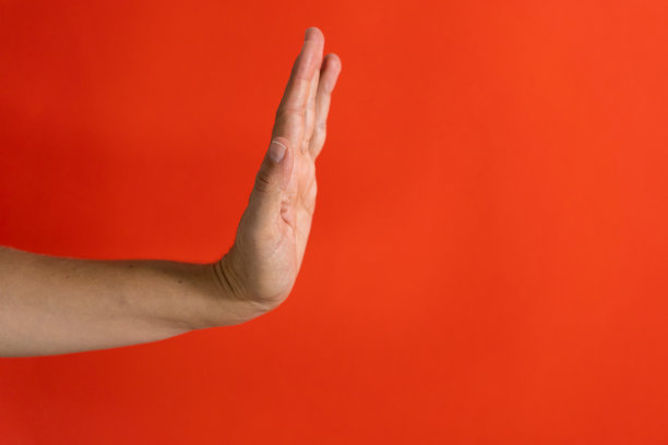 工作室的照片，一个女人的手显示停止手势和标志孤立在一个红色背景拒绝停止的概念。图片下载