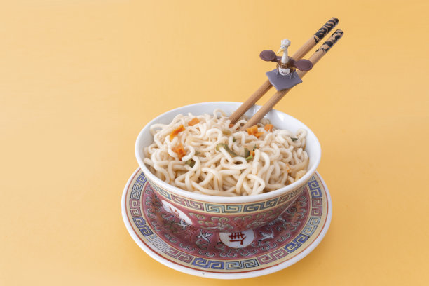 宝先生玩具的养父从动画喜剧功夫熊猫和筷子，在面条碗与柔和的橙色背景图片下载