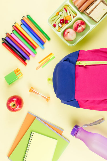 学校观念平铺。儿童背包，午餐盒，水瓶，笔记本，木桌上的马克笔图片下载