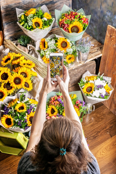 花店的照片上的智能手机美丽的向日葵花束。垂直拍摄图片下载