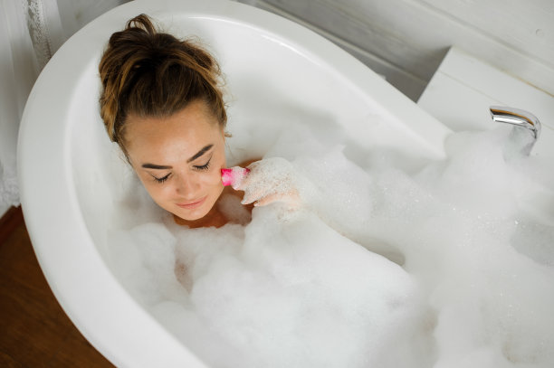 俯视图肖像的年轻和美丽的女人躺在浴池泡沫图片下载