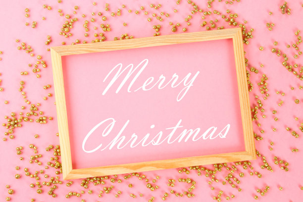 圣诞快乐。一个木制的空框架，在柔和的背景上，周围是闪亮的装饰星星和球。图片下载