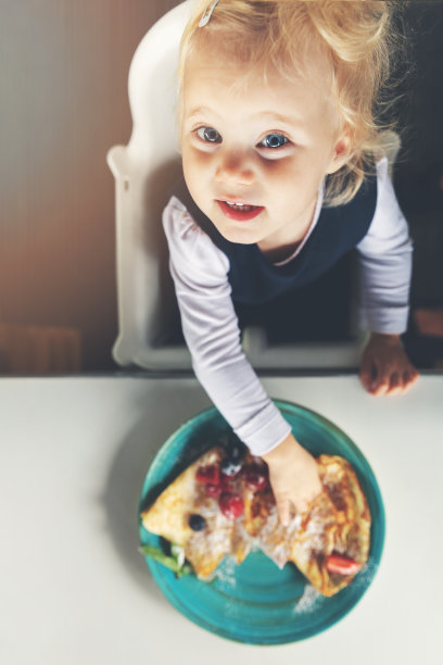 2岁的孩子在吃煎饼。俯视图图片下载